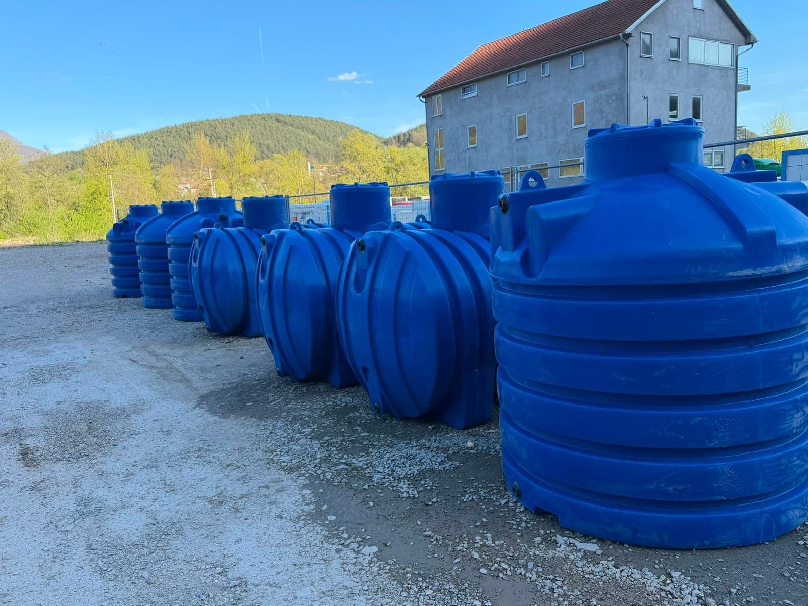 Plastične cisterne na platou, kuće u pozadini
